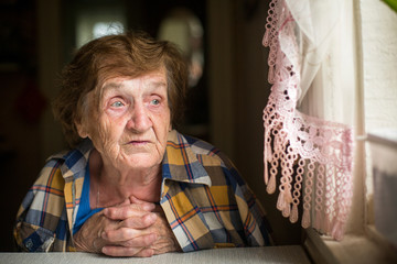 Old woman sitting at a table in his house