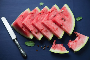 Sliced watermelon over dark blue wooden background, above view