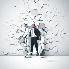 Young businessman breaking trough a wall