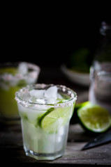 Water with ice and limes on rustic background
