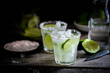 Water with ice and limes on rustic background
