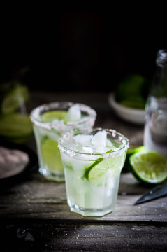Water with ice and limes on rustic background