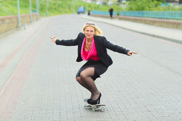 Senior business woman having fun on a skateboard outdoors