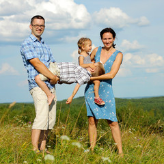 happy young family of four having fun on the top of a hill 