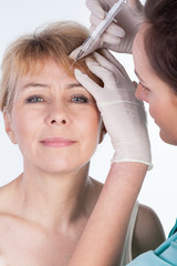 Fototapeta premium Cosmetic injection in mature woman's forehead
