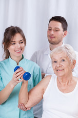 Physiotherapist insuring senior during exercise