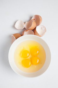 Top view of four egg yolks in white bowl and
