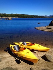 Fototapeta premium Two yellow kayaks on the shore of a beautiful lake.