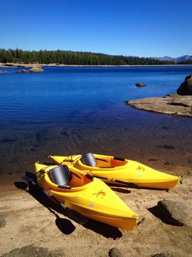 Two Yellow Kayaks On The Shore Of A Beautiful Lake.