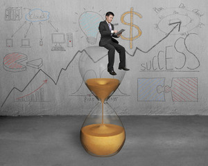 businessman use tablet and sit on hour glass