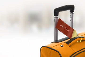 New Delhi. Orange suitcase with label at airport.