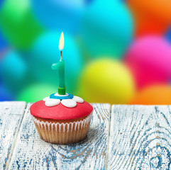 Cupcake with number one on the background of balloons