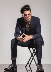 elegant man with glasses sitting on chair
