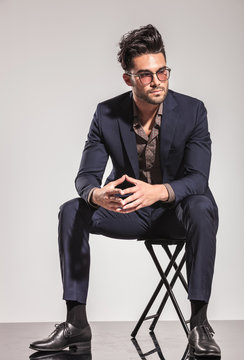 Fashion Man In Suit Sitting And Looks To  Side