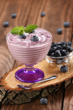 yogurt with blueberries in a glass bowl and blueberries in a gla