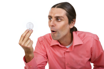 Young man an with surprised looks at a light bulb