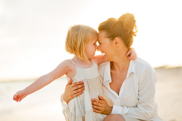 Portrait of happy mother and baby girl hugging on the beach