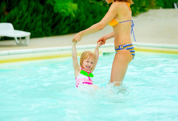 Mother and baby girl playing in swimming pool