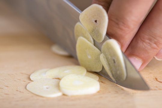 Cocinero cortando ajos laminados en lonchas en la cocina