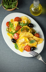 Italian ravioli with olives, tomato and rocket