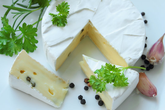 Camembert cheese with fresh herbs on a white plate