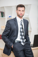 Portrait of handsome confident businessman sitting on his table