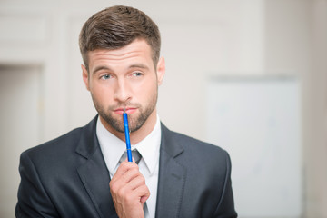 Portrait of handsome businessman in office interior touching his