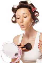 happy housewife with curlers to apply makeup on her cleavage