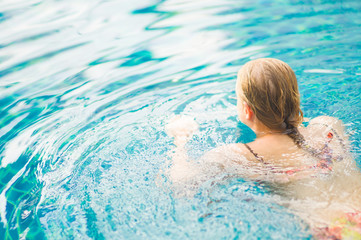 Fototapeta na wymiar Young woman start to swim in tropical beach resort pool