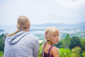 Mother and daughter look around from mountain view point on trop
