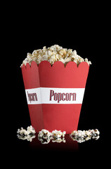 Popcorn in a red paper cup on a black background