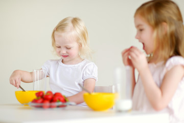 Two sisters eating cereal with milk