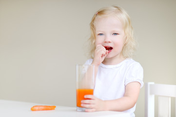 Adorable toddler girl eating carrots