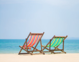 Bright color wooden beach chairs on island tropical beach