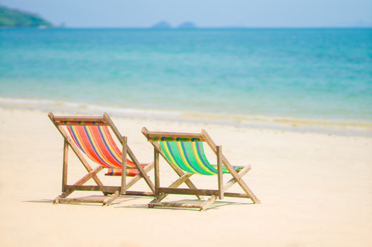 Bright color wooden beach chairs on island tropical beach