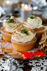 Christmas cupcakes with cream on a table decorated with Christma