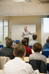 presenter near the screen and people sitting rear