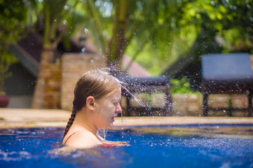Fototapeta premium Young woman relax in pool under water shower stream fall to head