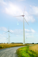 Wind turbine generators in a field against blue sky