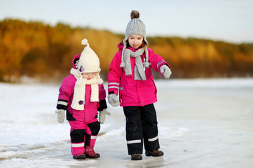 Two little sisters having fun on snowy winter day