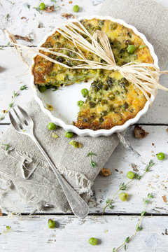 rustic vegetables quiche with peas on baking dish with fork