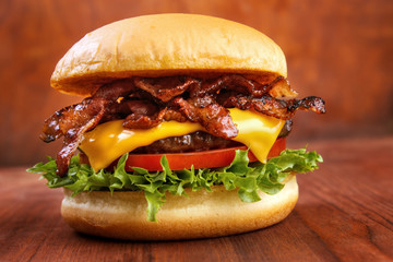 Fototapeta Bacon burger with beef patty on red wooden table obraz