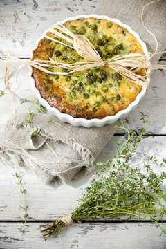 vegetables quiche with peas on baking dish with thyme bouquet