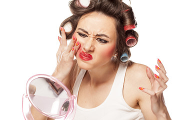 nervous woman with curlers removes makeup with her hands