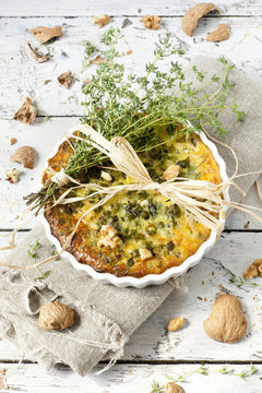 quiche with peas and walnuts on baking dish with thyme bouquet