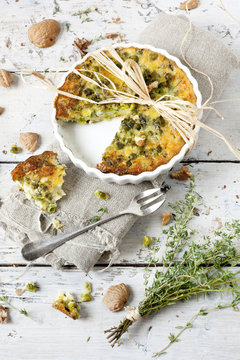 quiche with peas and walnuts on baking dish with thyme bouquet
