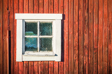 Square white window in old red wooden barn wall