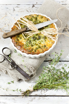 rustic french quiche with peas with thyme bouquet and scissor