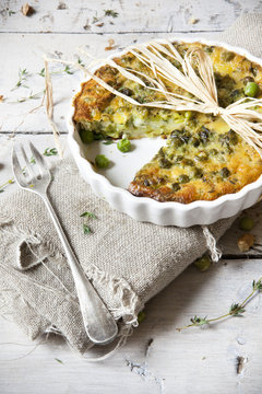 vegetables quiche with peas on baking dish with fork
