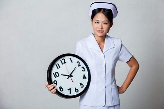 Young Asian nurse with clock
